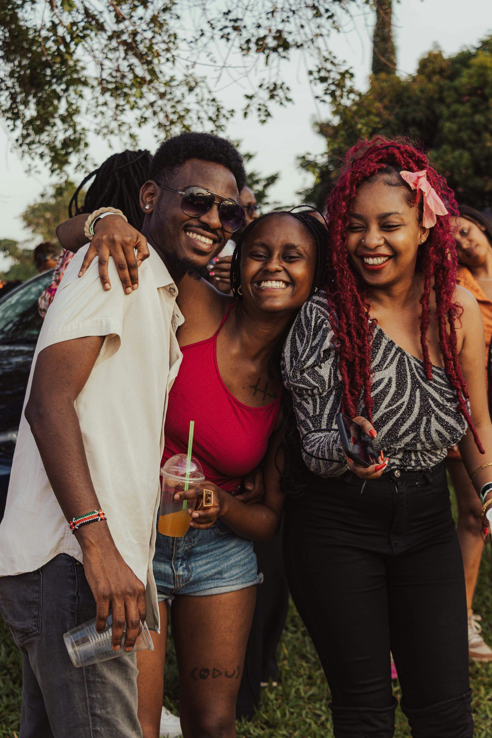 Three friends laughing together outdoors with their arms around each other